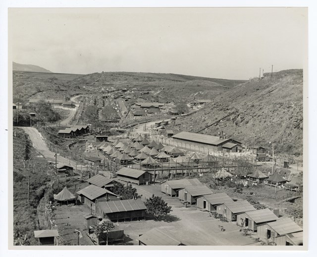 A historic photo of a valley filled with tents and wooden buildings