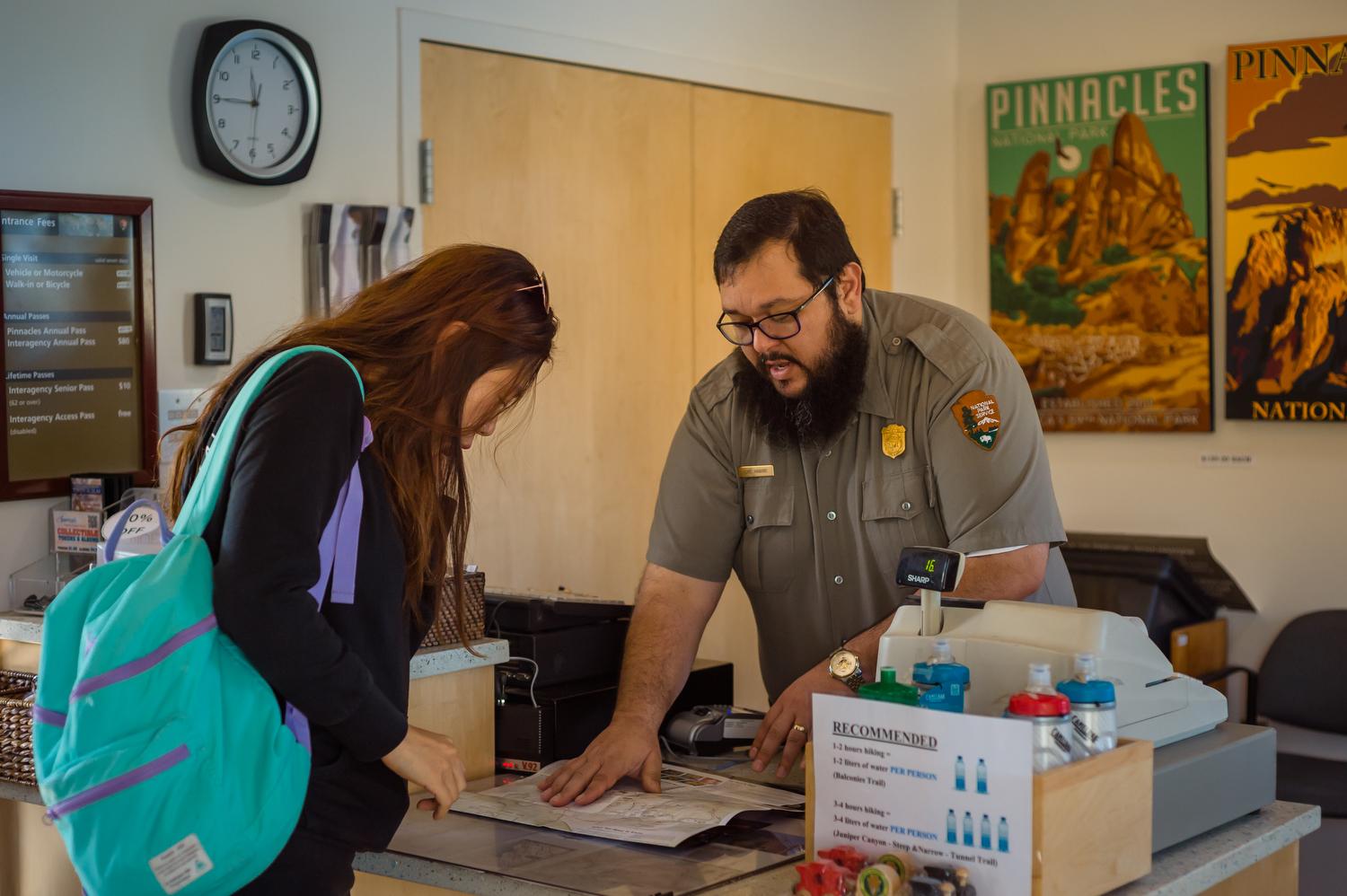 A park ranger helping a visitor look at the park map in a visitor center