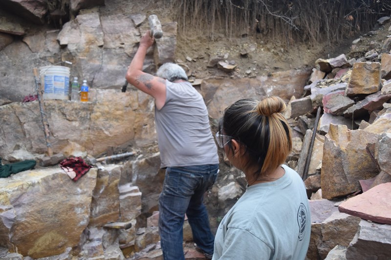 Breaking Through A man in a quarry pit swings a hammer as a woman watches
