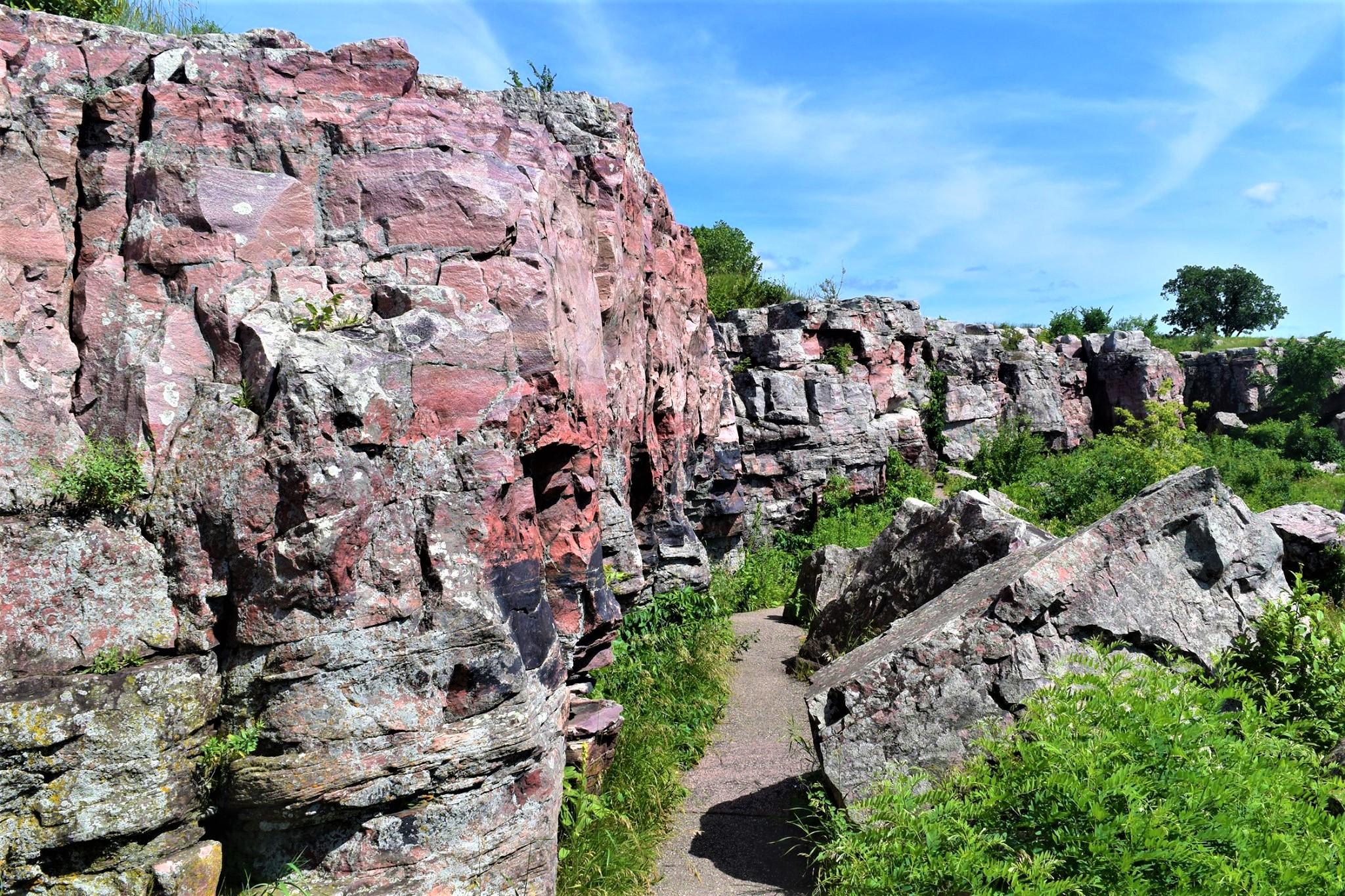 Pink wall of rock next to path and grass