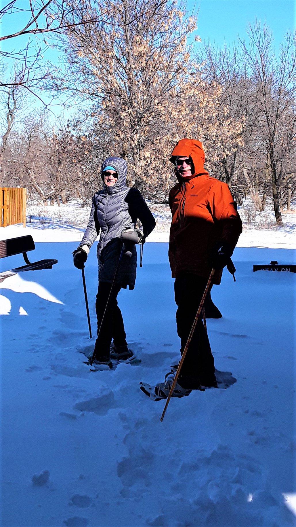 A couple outside in snowshoes smiling at the camera