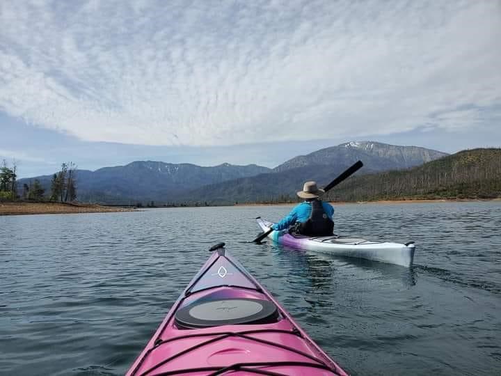 Two kayakers paddling on Whiskeytown Lake. Clouds above.