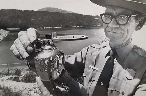 Park ranger with flat hat holding a small commemorative jug