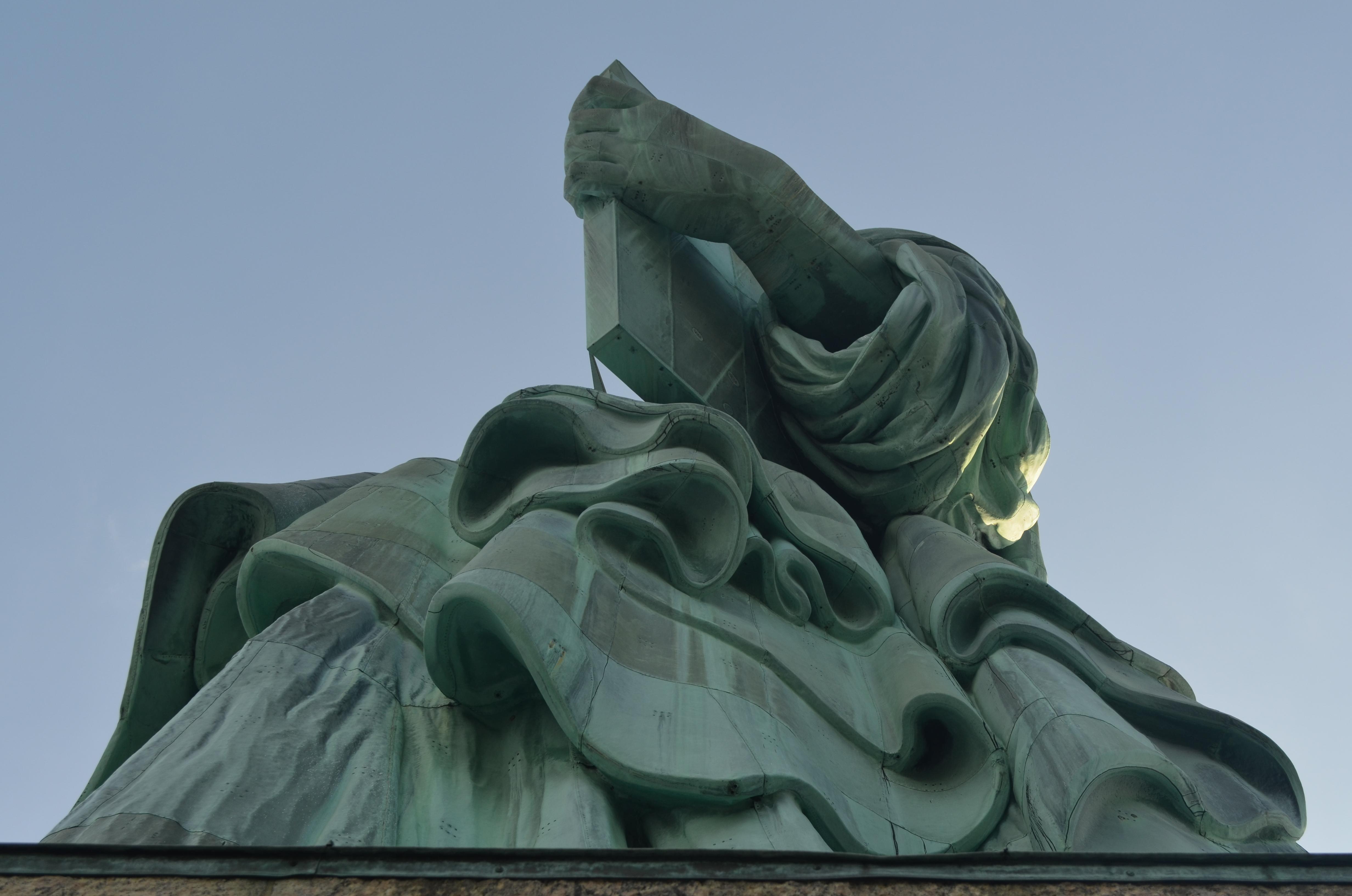 The folds of the Statue of Liberty's dress are seen with the left hand holding the tablet.
