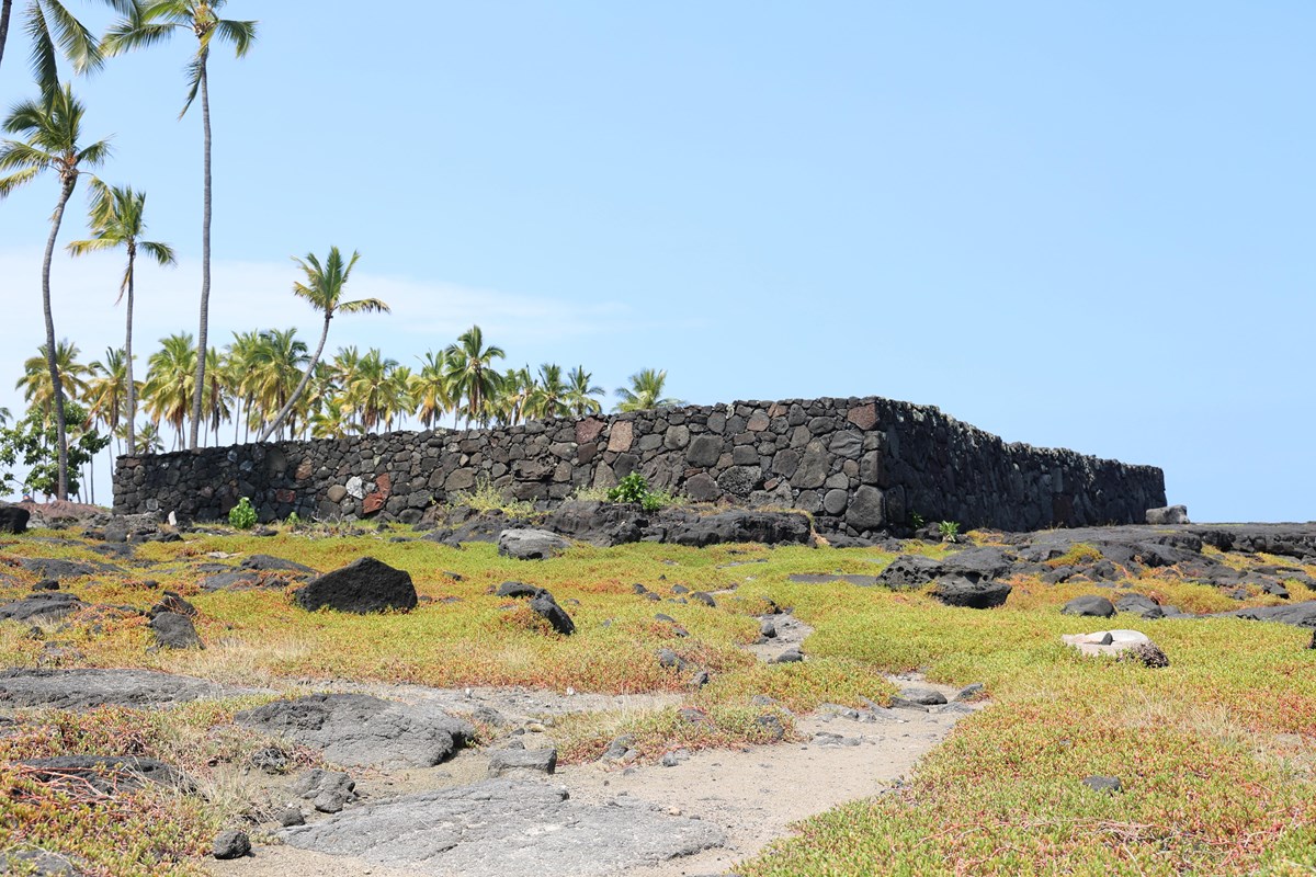 A large heiau at the end of a sandy path.