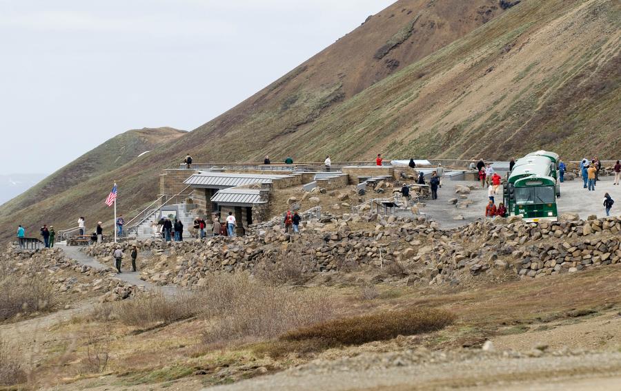A low profile building set into a mountainside, with many people walking around the area.