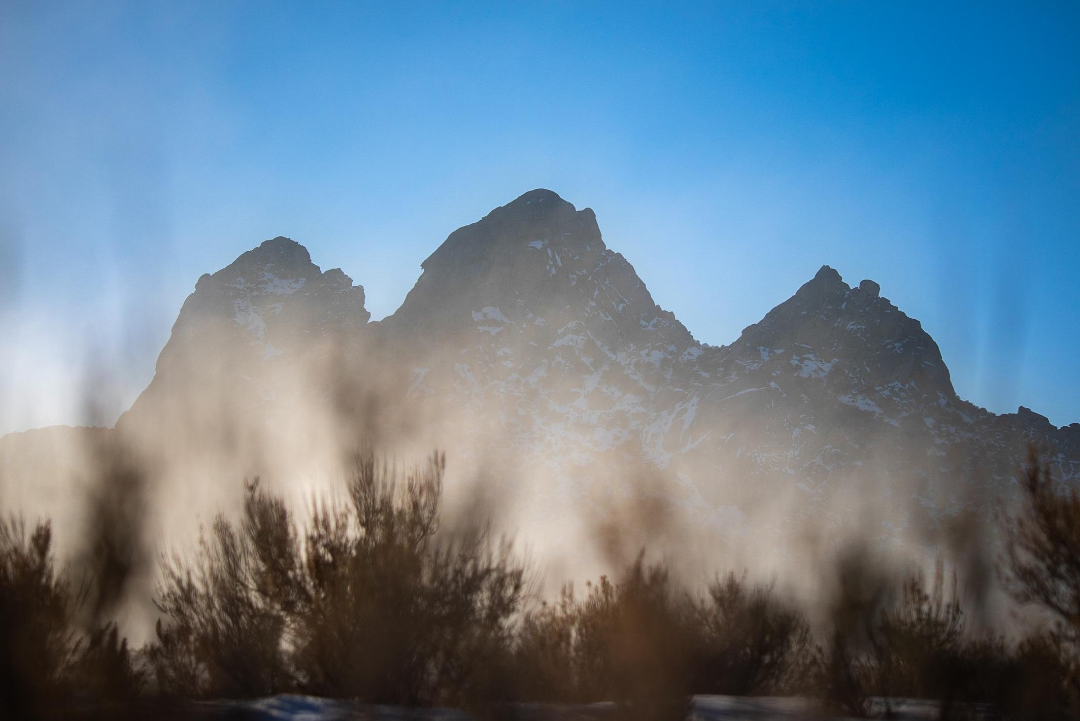 3 silhouetted foggy granite formations highlighted by golden sunlight.