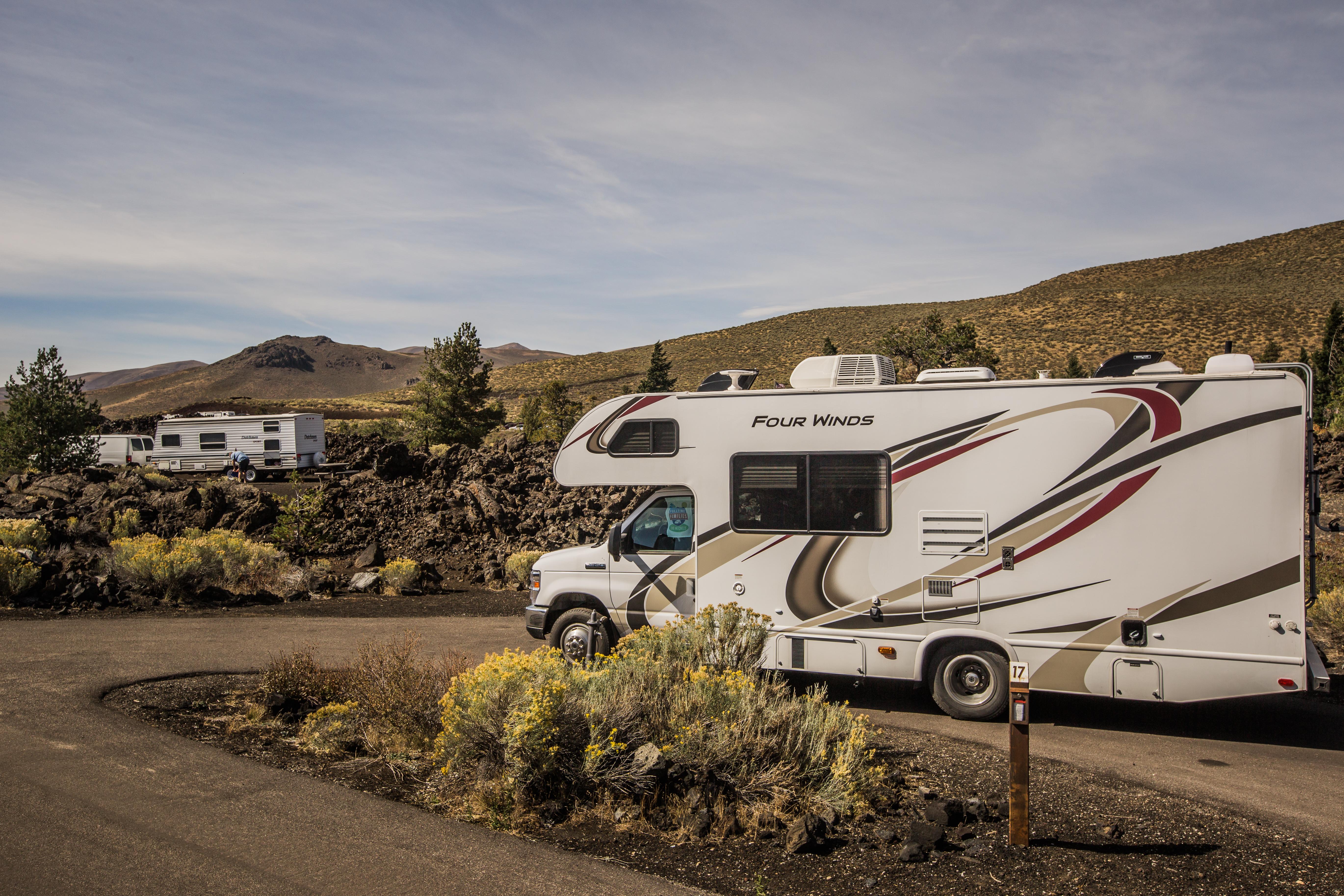 an RV parked in a pull through campsite among sagebrush, a second RV is at the neighboring site