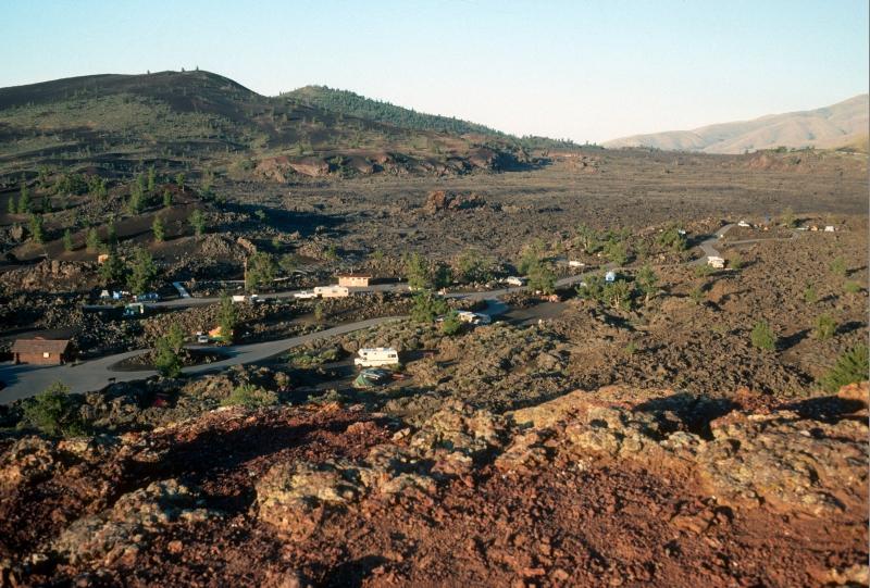 trailers, RVs, and other vehicles parked at different sites at a small campground among lava rocks