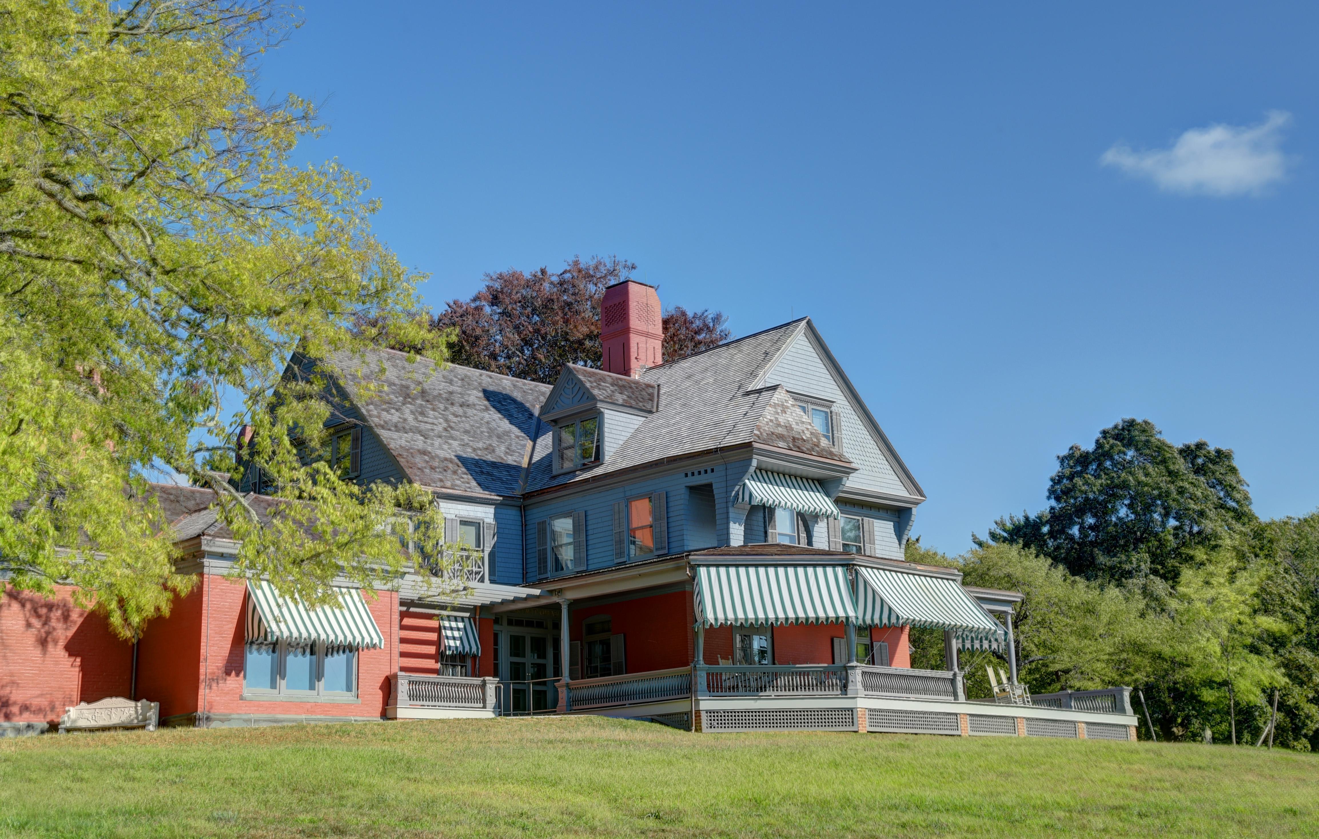 A large house painted gray with green lawn and trees.