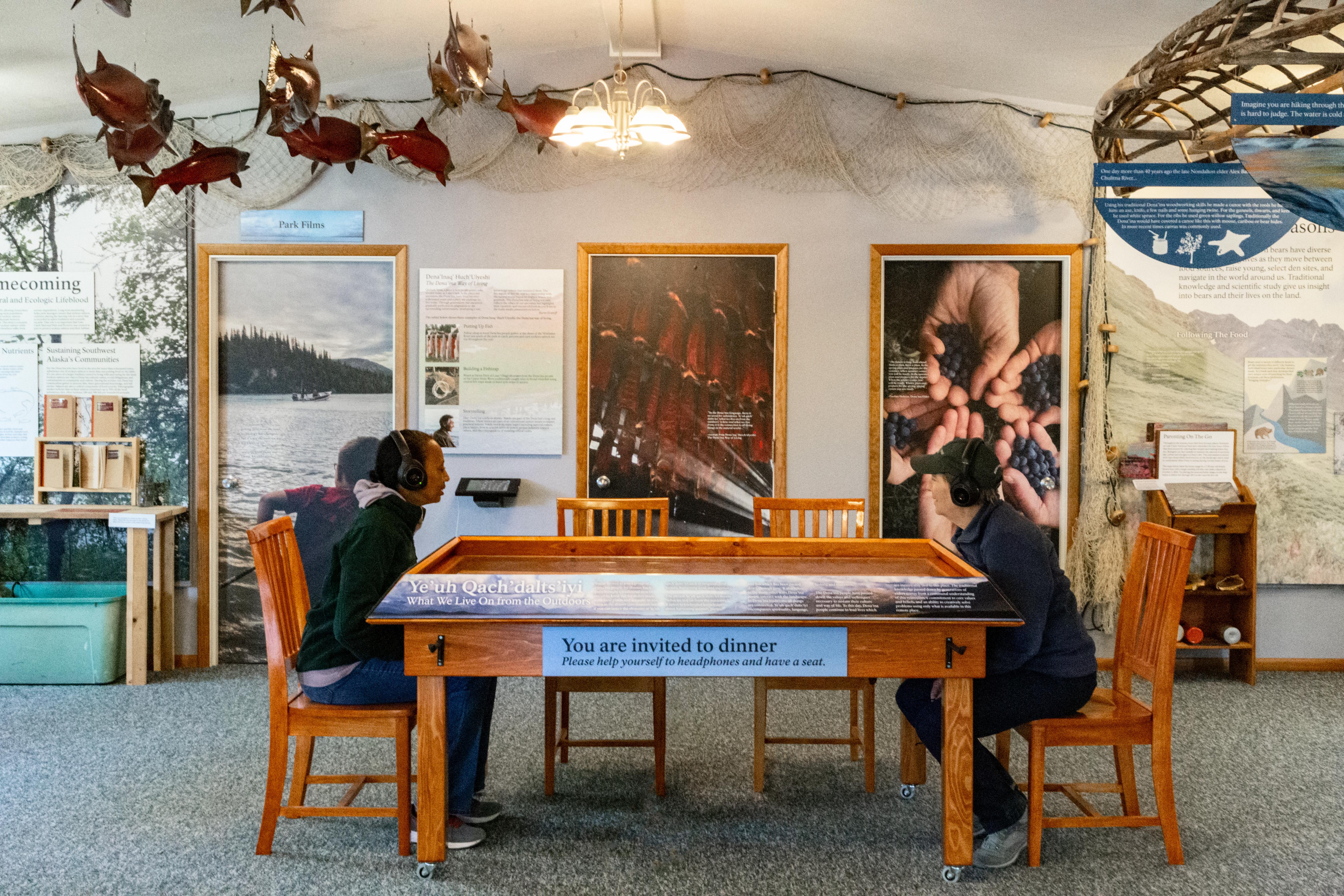 Two people sit at a table exhibit inside the visitor center.