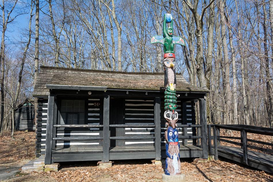 A one story building with trees behind them and a totem poll in front.