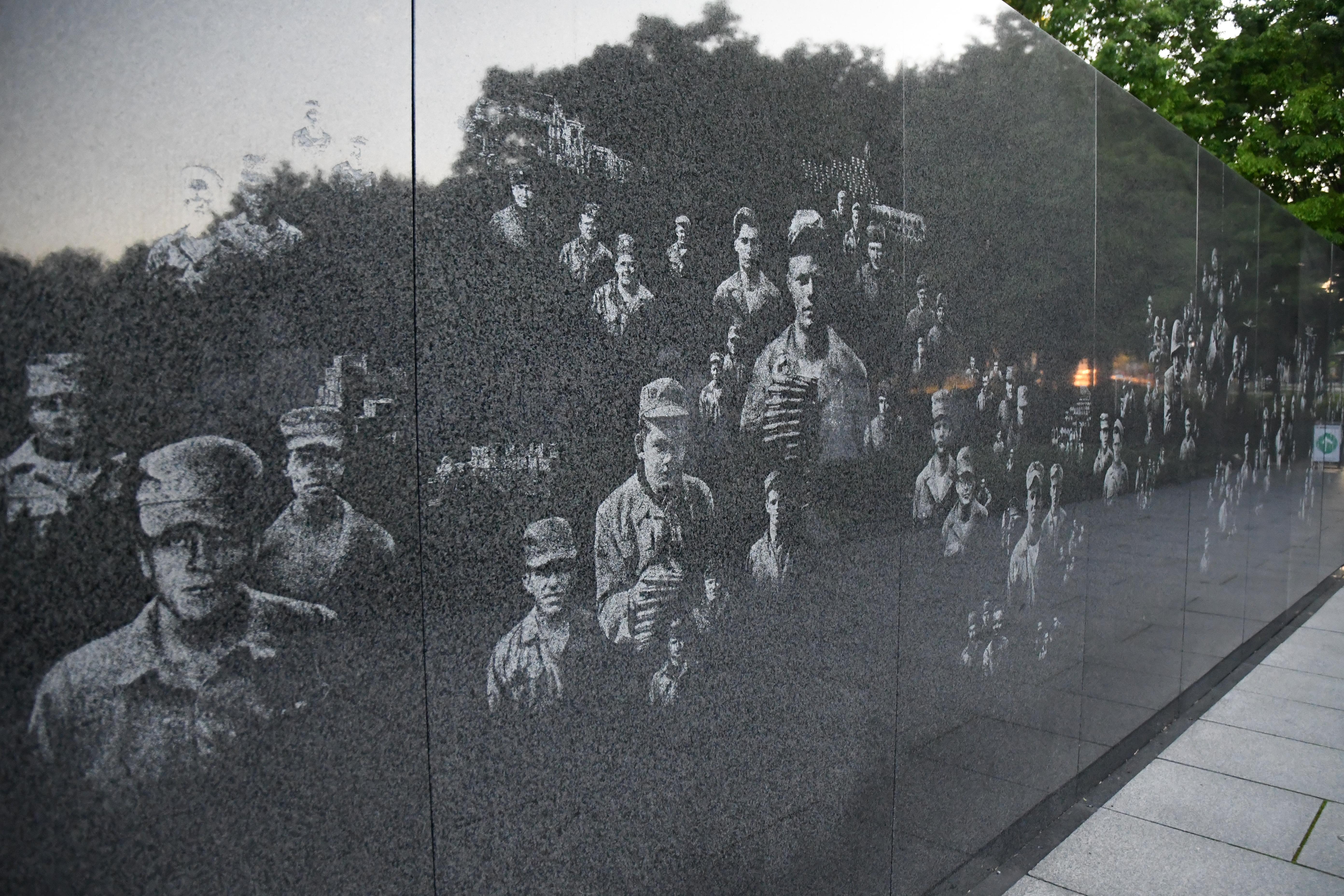 Faces of soldiers are etched onto a black granite wall