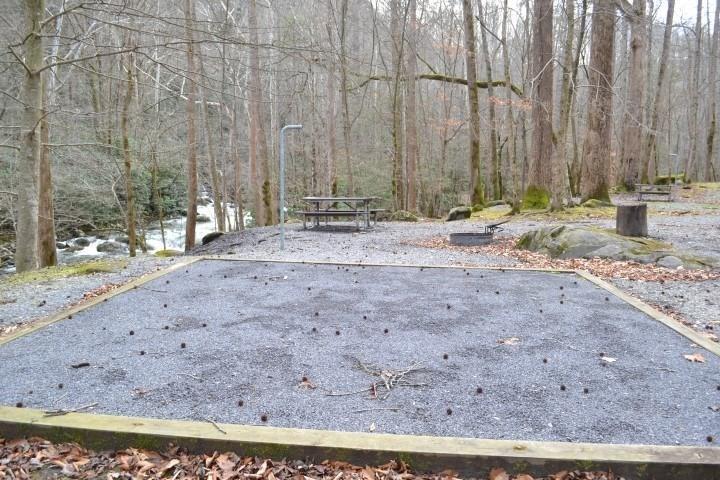 A wooded campsite with gravel tent pad