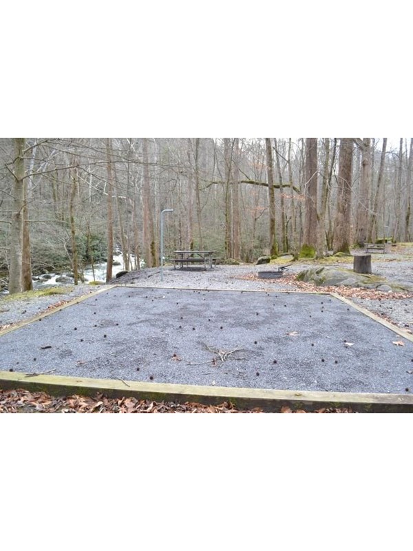 A wooded campsite with gravel tent pad