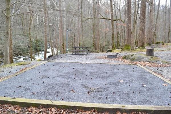A wooded campsite with gravel tent pad