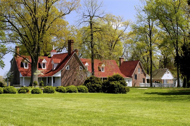 Image of a large historic house with green lawn in foreground.