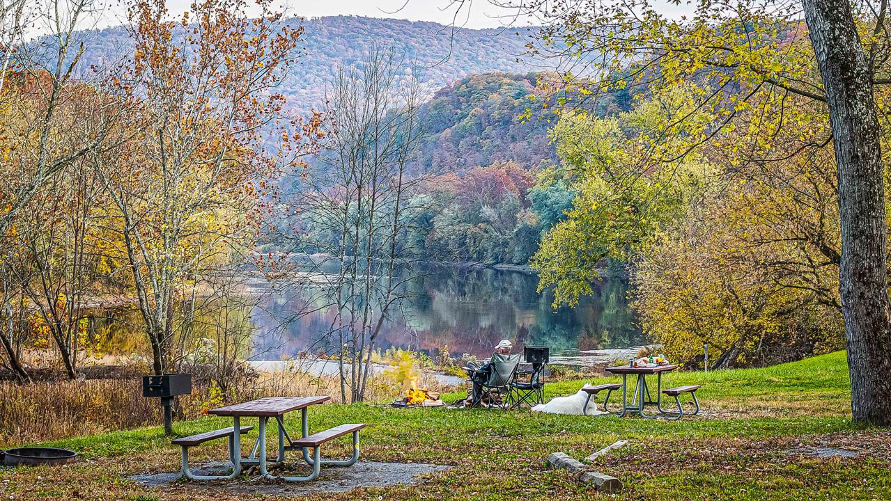 A picnic table and camp stove lined by trees with the Potomac River in the background.