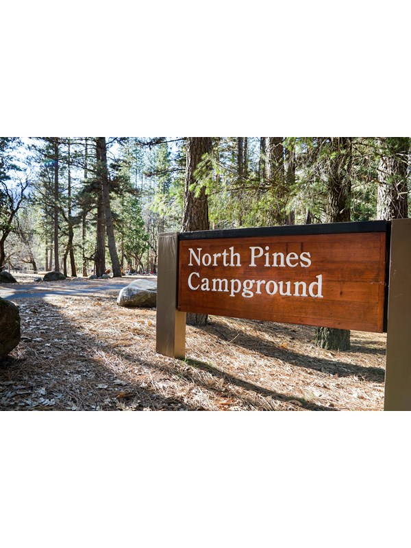 A wood sign at the entrance of a campground reads, North Pines Campground.