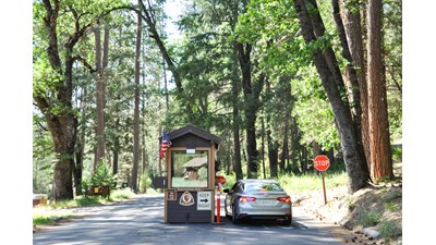 A car is stopped at a small kiosk at the entrance to a campground.