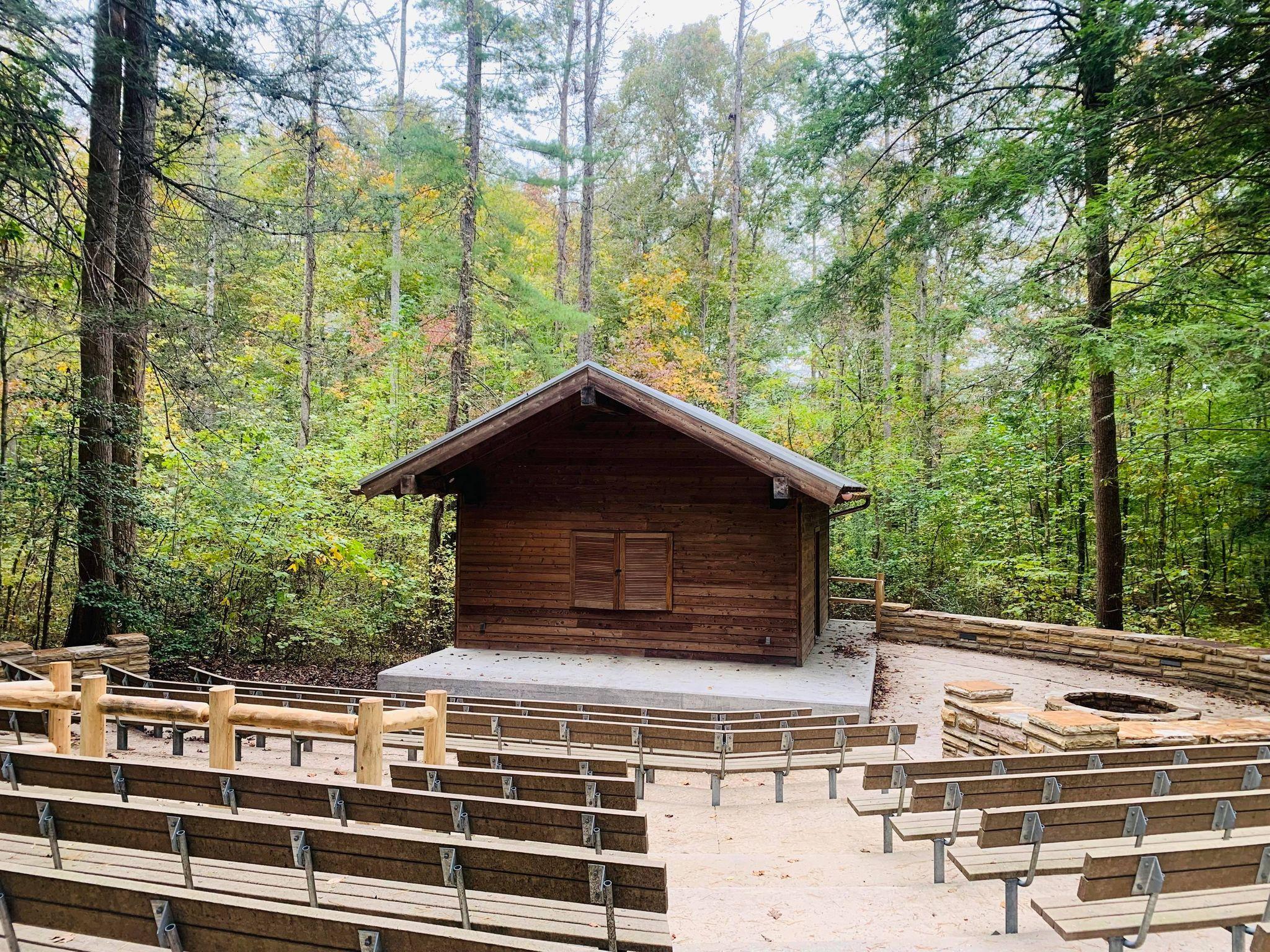 Brown cabin used as an amphitheater with benches around it.