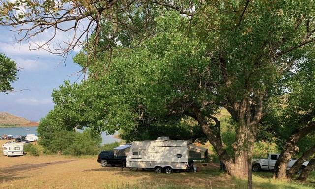 A camper at Cedar Canyon underneath cottonwood trees near the lake.
