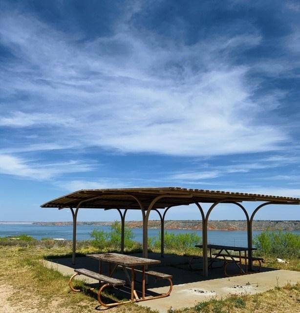 A picnic area at Blue West overloooking the lake.  The sky is blue with white clouds.