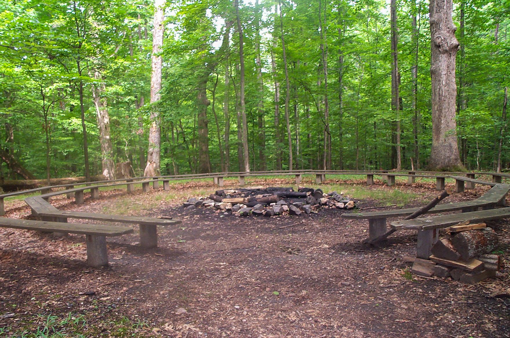 Wooden benches surround a large fire pit in a circle