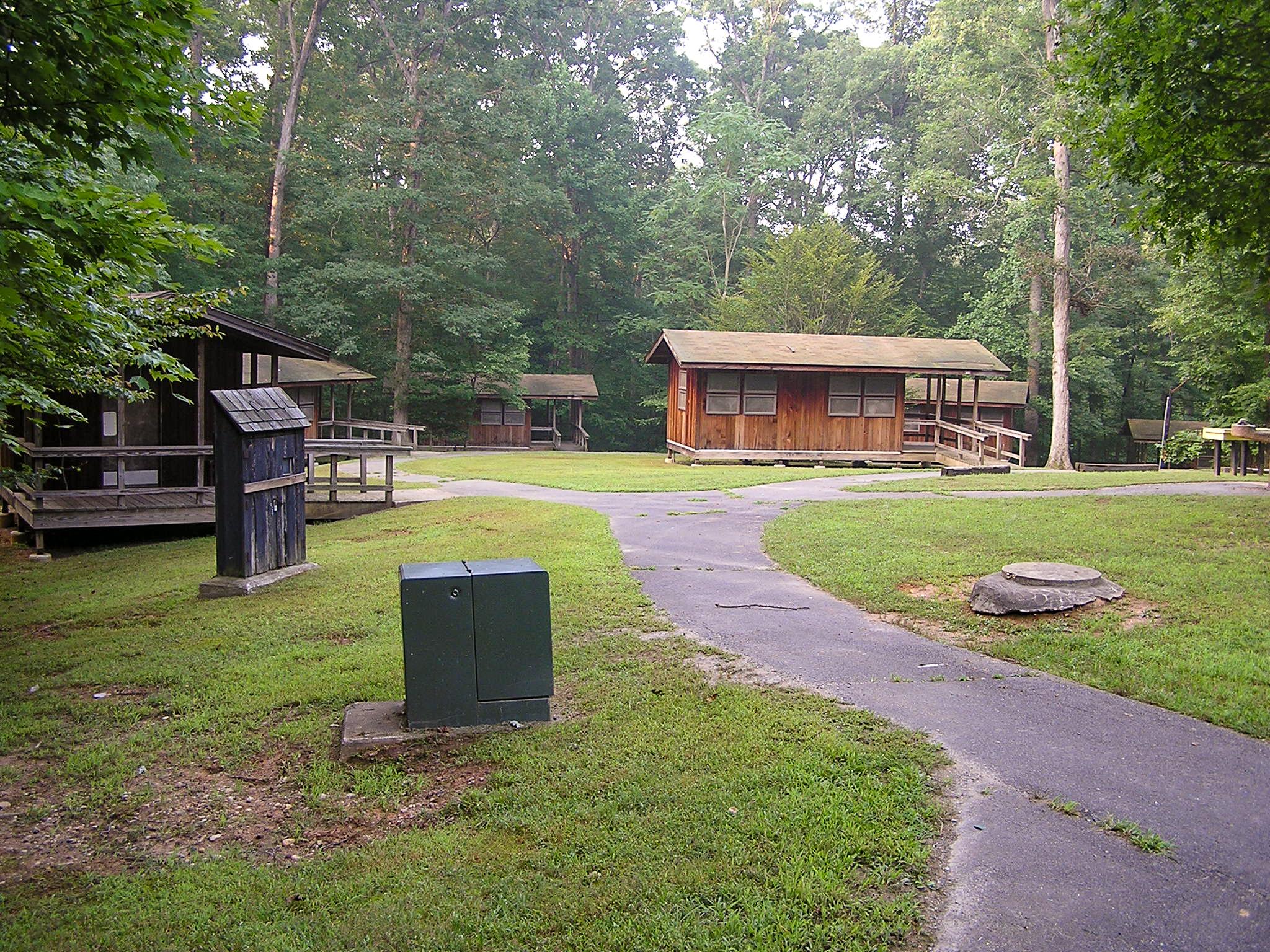 A concrete sidewalk leads the way to five brown, wooden sleeper cabins