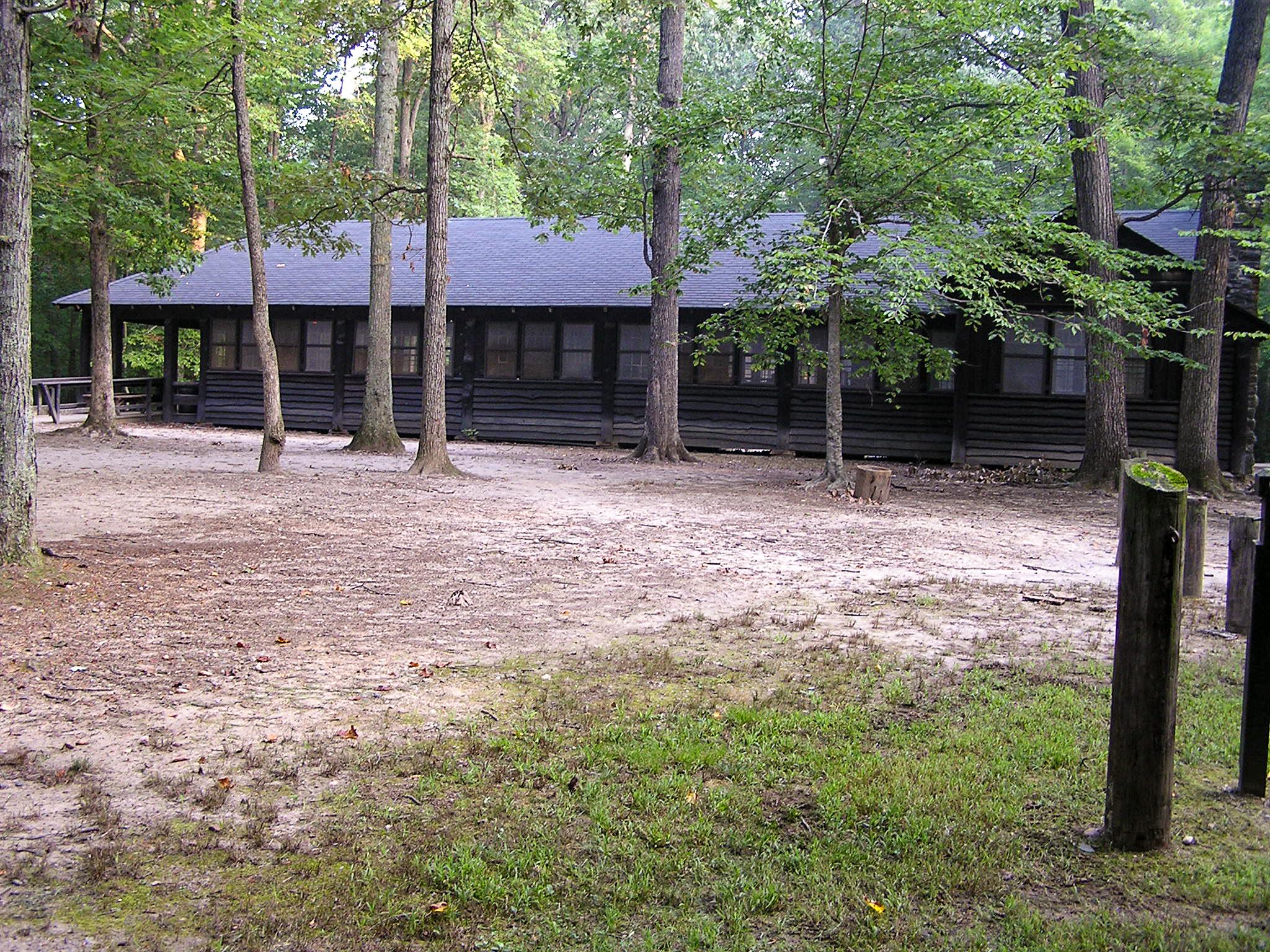 A dark brown wood building sits among the woods