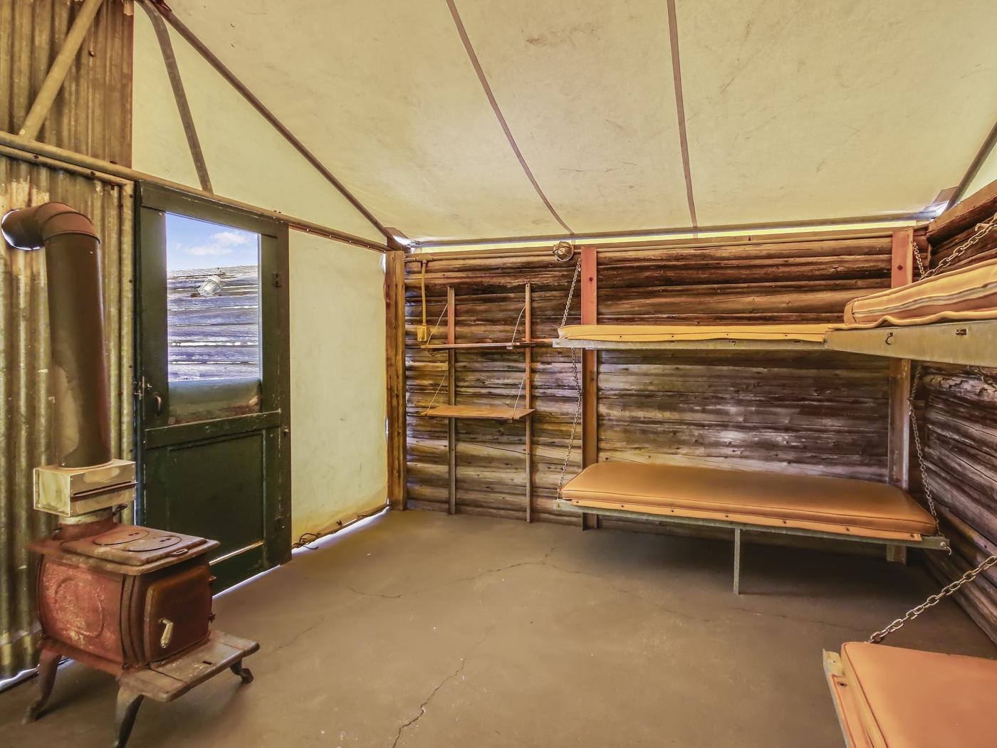 Canvas roof with log walls, wood stove, and bunk beds
