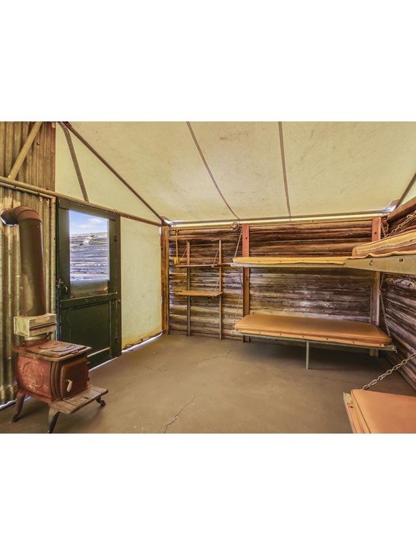 Canvas roof with log walls, wood stove, and bunk beds