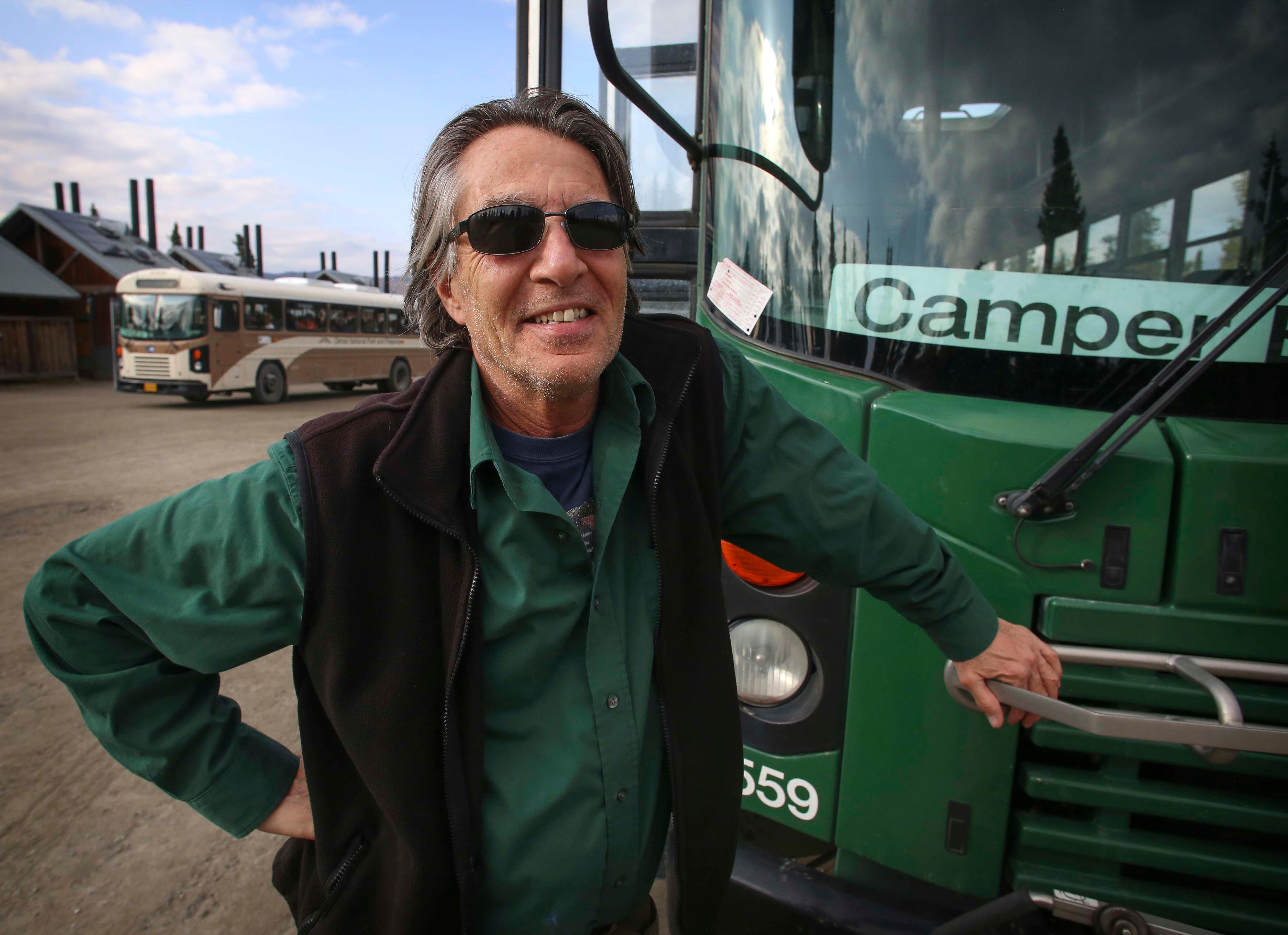 a man standing next to a green bus