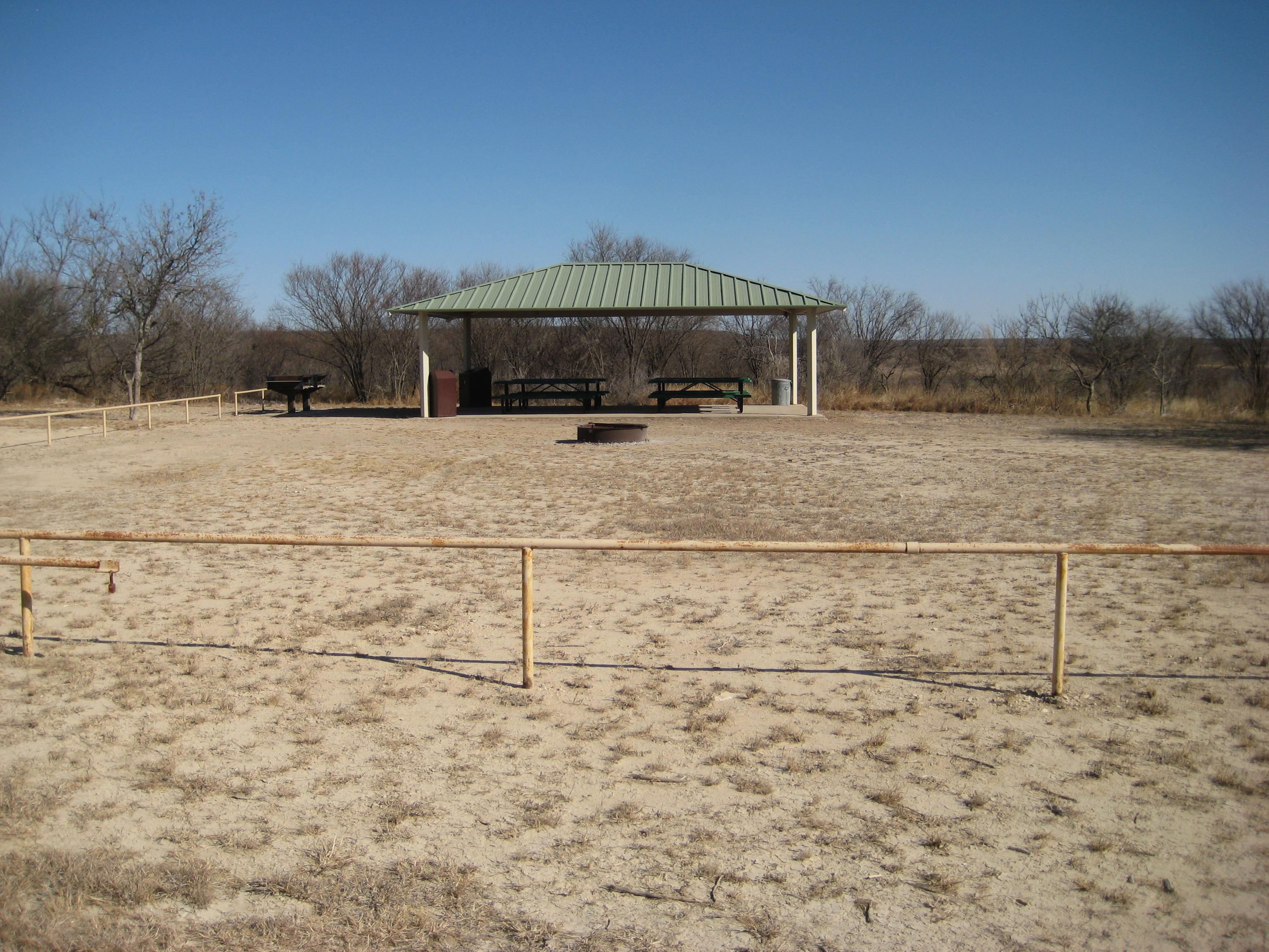 Open space with a fire pit and covered picnic area for the group campsite.