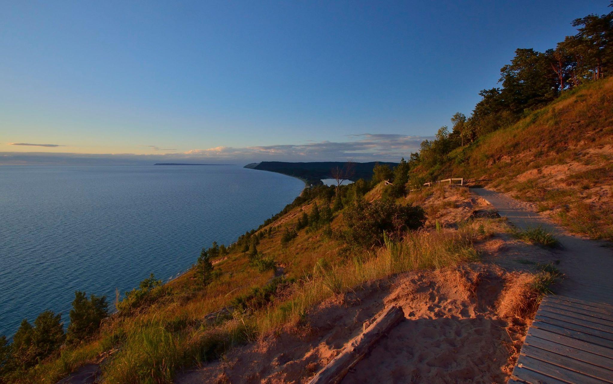 A trail overlooking a large lake at sunset