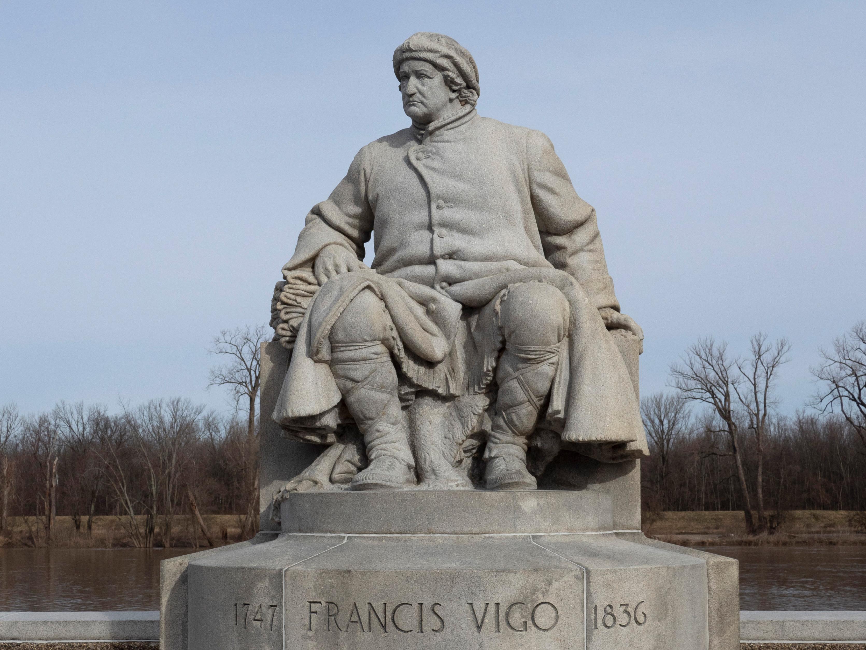 A granite statue of Francis Vigo, seated, dressed in 18th century fur trader clothing