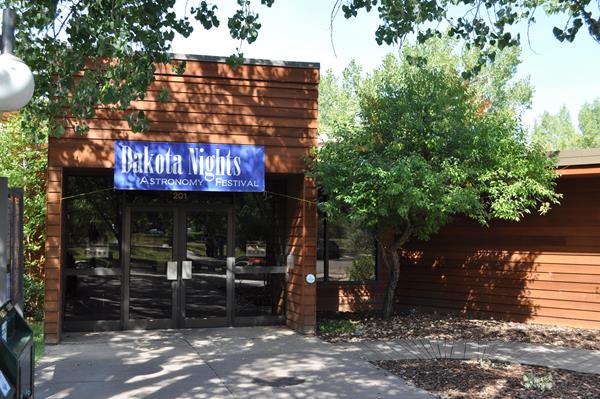 Building in dappled sunlight with banner across front.