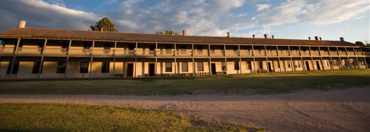 A large, long tan building with many windows with the sun shining on it