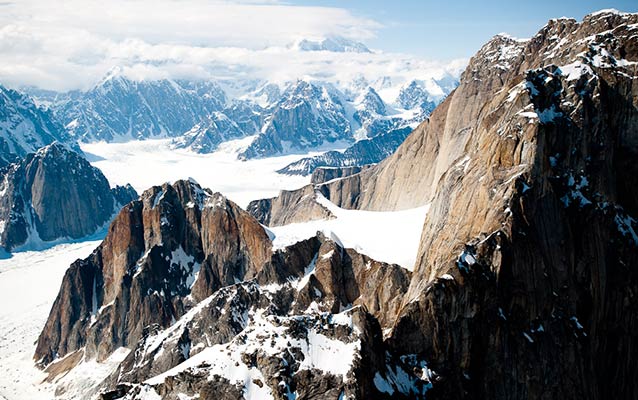 aerial image of glaciers, steep mountains, and Denali shrouded in clouds