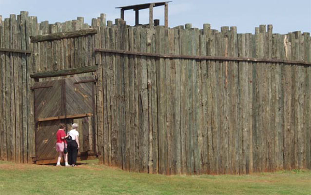 Visitors stand next to large wooden gate Visitors stand next to large wooden gate