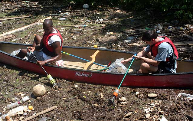 Two paddlers in the midst of trash on the river. Where does it end?