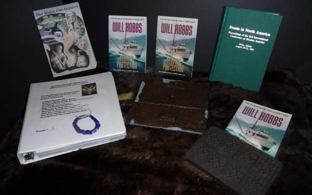 Books, educational materials and learning tools such as trade beads and tea bricks all resting on top of a large piece of sea otter fur.