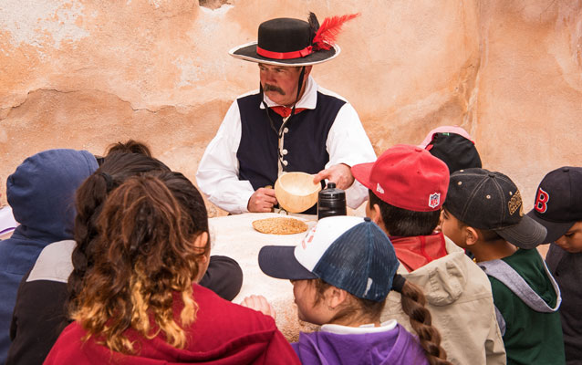 students speaking with man in living history costuming