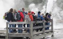 A school group and ranger near a thermal feature with steam in background