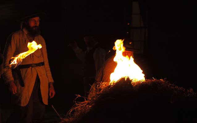 Reenactor portraying James Montgomery lighitng a wagon of hay on fire