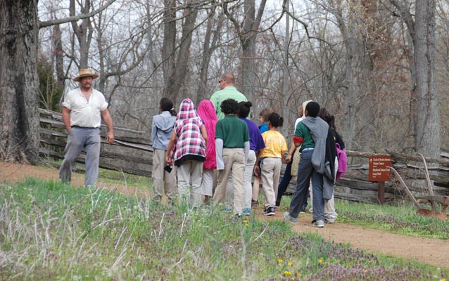 Park ranger meets educational group on the trail to the farm.