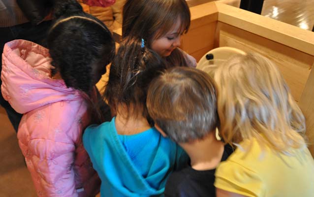 A photo of five children peeking into one of the barrels at the C&O Canal Museum at Canal Place