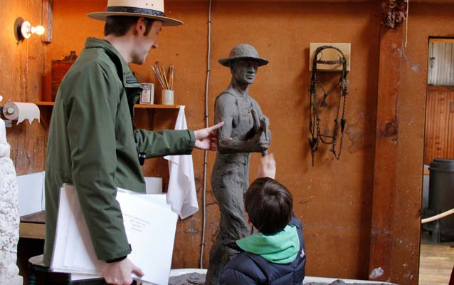 A student and park ranger touch a reproduction sculpture in the Young Studio.