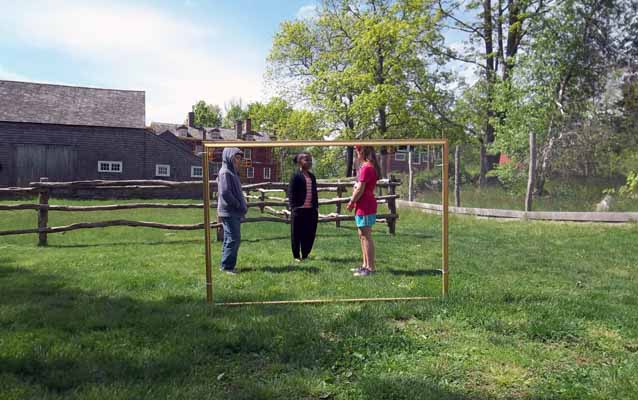 Students act out a skit in a giant frame placed in a historic painting site.