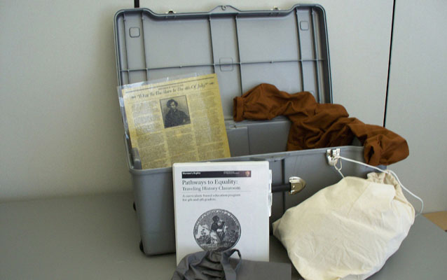Picture of an opened Traveling Trunk with some of its contents on display.